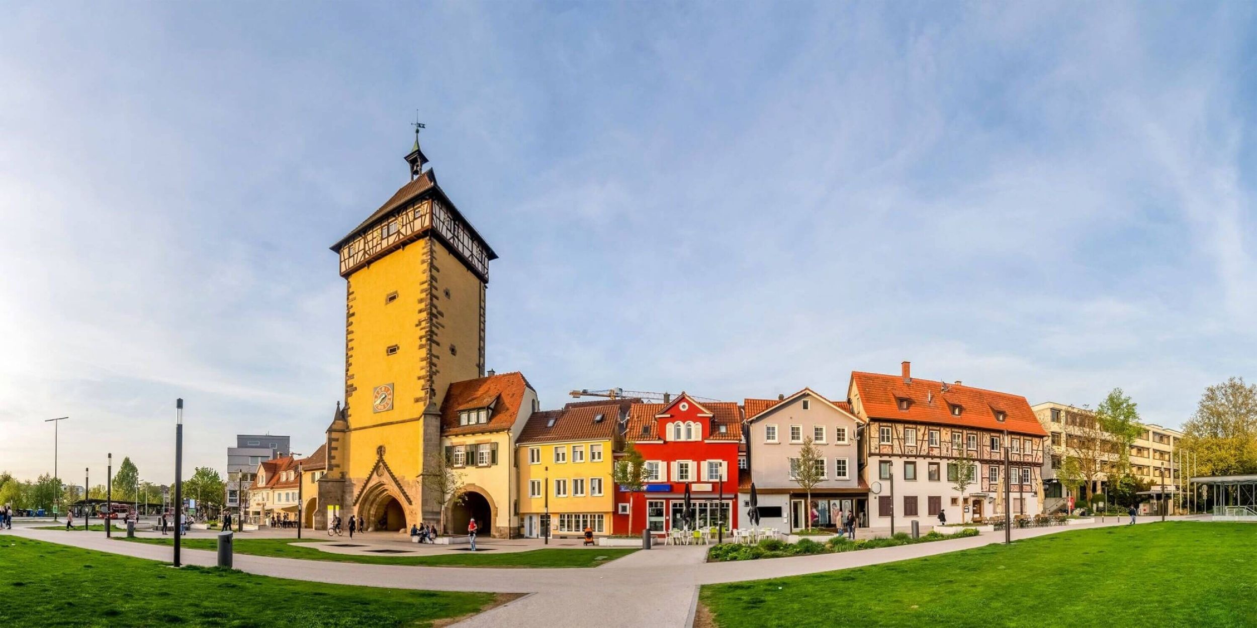 Panoramablick auf einen europäischen Stadtplatz mit bunten Gebäuden und einem Uhrenturm.